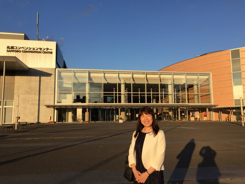 学会の建物の前で立っている入江泰子の写真